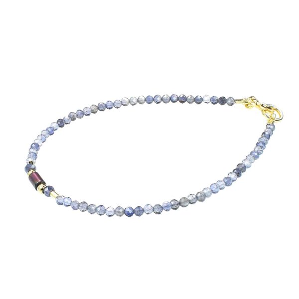 Handmade bracelet with natural, faceted, spherical shaped iolite gemstones and one cylindrical oxidized agate element in the center. The bracelet has decorative elements and clasp made from gold plated sterling silver.