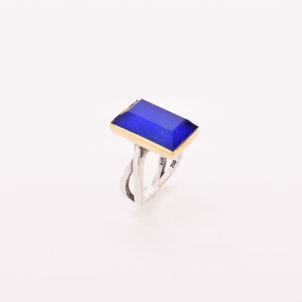 Handmade sterling silver and gold ring with doublet made of crystal quartz and lapis lazuli gemstones, in a parallelogram shape. The band of the ring is made of sterling silver and the outline of the bezel is made of 18 carats gold. The doublet consists of two layers of stones. The upper stone is crystal quartz and the stone at the bottom is lapis lazuli.