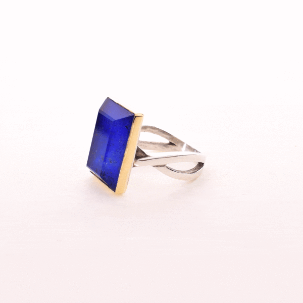 Handmade sterling silver and gold ring with doublet made of crystal quartz and lapis lazuli gemstones, in a parallelogram shape. The band of the ring is made of sterling silver and the outline of the bezel is made of 18 carats gold. The doublet consists of two layers of stones. The upper stone is crystal quartz and the stone at the bottom is lapis lazuli.