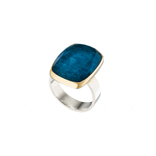 Handmade silver and gold ring with doublet made of crystal quartz and apatite, in a parallelogram shape. The bezel of the ring is made of 18 carats gold and the band is made of sterling silver. The doublet consists of two layers of stones. The upper stone is crystal quartz and the stone at the bottom is apatite. Buy online shop.