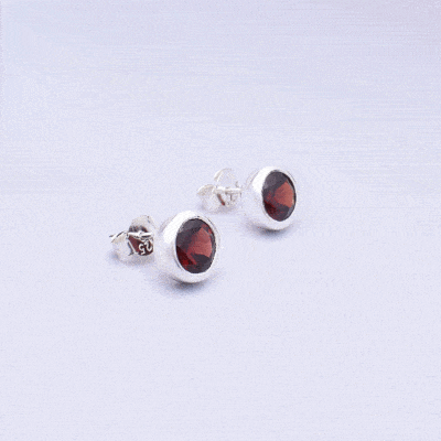 Handmade stud earrings made of sterling silver and natural, faceted garnet gemstone in a round shape. Buy online shop.