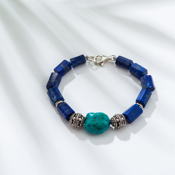 Handmade bracelet with natural lapis lazuli gemstones and one central turquoise gemstone, threaded on a blue string in which there are some knots between the stones. The bracelet is decorated with elements made of sterling silver and it has a sterling silver clasp. Buy online shop.