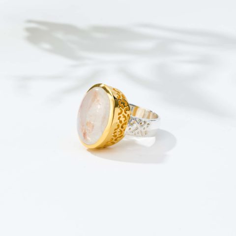 Χειροποίητο δαχτυλίδι από ασήμι 925 με επιχρυσωμένο περίγραμμα και φυσική πέτρα λευκού λαμπραδορίτη οβάλ σχήματος. Το δαχτυλίδι έχει διάτρητα σχέδια στη γάμπα και στο καστόνι του. Αγοράστε online shop.