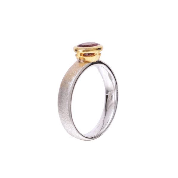 Handmade ring made of sterling silver and natural pink tourmaline gemstone, in an oval shape. The bezel of the ring is gold plated and the surface of the band is textured. Buy online shop.