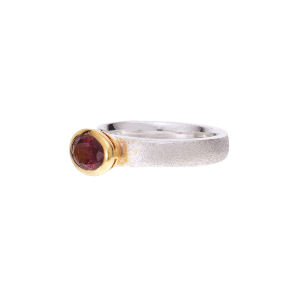 Handmade ring made of sterling silver and natural pink tourmaline gemstone, in an oval shape. The bezel of the ring is gold plated and the surface of the band is textured. Buy online shop.