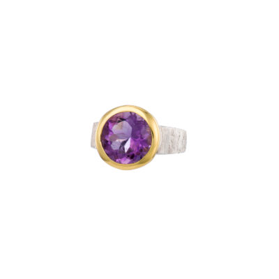 Handmade ring made of sterling silver and natural amethyst gemstone in a round shape. The ring has textured band and gold plated bezel. Buy online shop.