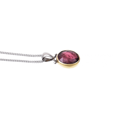 Handmade pendant made of sterling silver and 18 carats gold with natural, faceted, round shaped pink tourmaline gemstone. The pendant is threaded on a sterling silver chain.