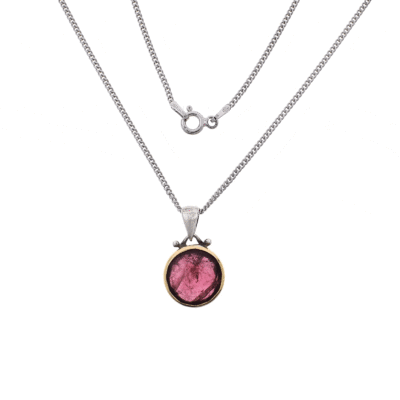 Handmade pendant made of sterling silver and 18 carats gold with natural, faceted, round shaped pink tourmaline gemstone. The pendant is threaded on a sterling silver chain.