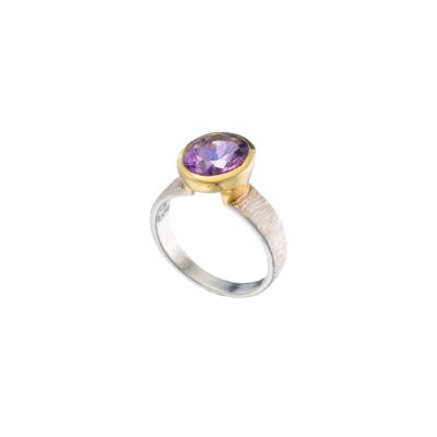 Handmade ring made of sterling silver and natural amethyst gemstone in an oval shape. The ring has textured band and gold plated bezel. Buy online shop.