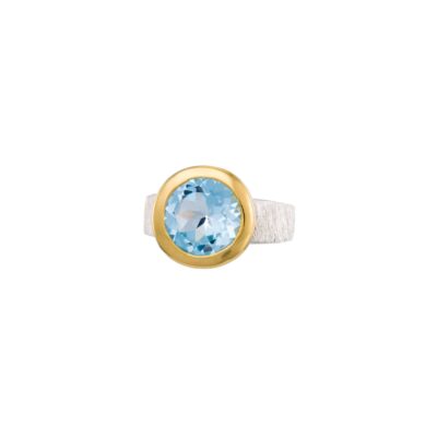 Handmade ring made of sterling silver and natural blue topaz gemstone in a round shape. The ring has textured band and gold plated bezel. Buy online shop.