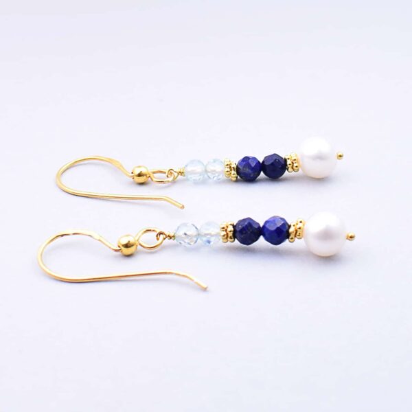 Handmade earrings made of gold plated sterling silver and natural, faceted, spherical shaped lapis lazuli and blue topaz gemstones, as well as a natural pearl in the end point. Buy online shop.